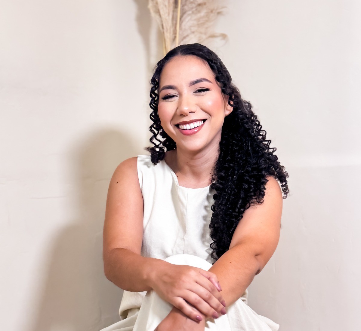 Kesia Cristina sorrindo, sentada com um vestido branco.