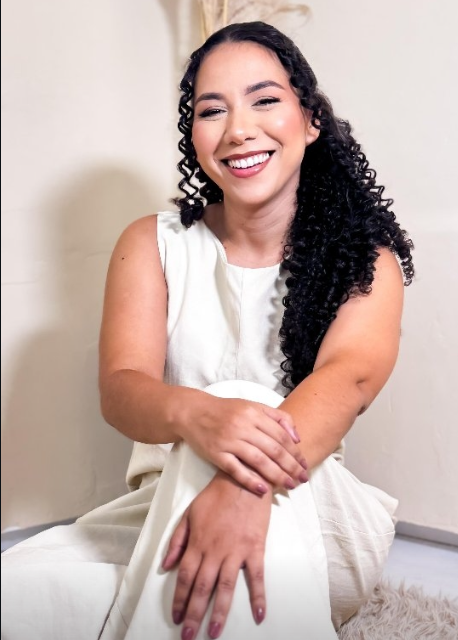 Kesia Cristina sorrindo, sentada com um vestido branco.
